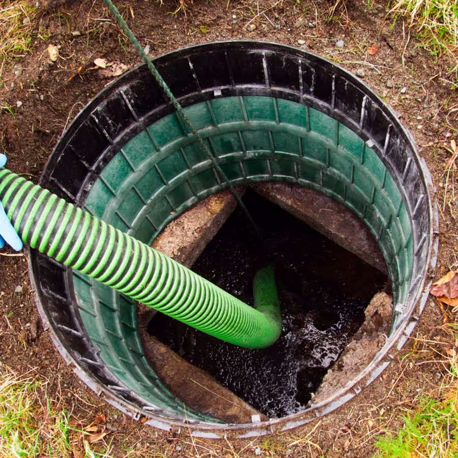 A vacuum hose lowered into a commercial pit for pumping